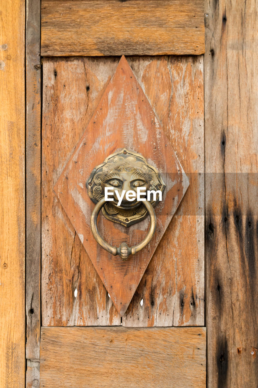 Metallic door knocker on wood
