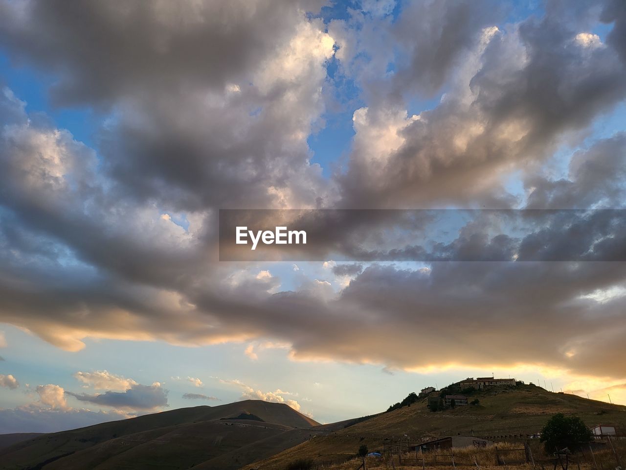 sky, cloud, environment, landscape, mountain, scenics - nature, beauty in nature, dramatic sky, nature, horizon, sunlight, sunset, land, dusk, cloudscape, no people, travel, travel destinations, outdoors, mountain range, storm, tranquility, non-urban scene, evening, moody sky, blue, tourism, tranquil scene, sunbeam, awe, overcast, dramatic landscape, horizon over land