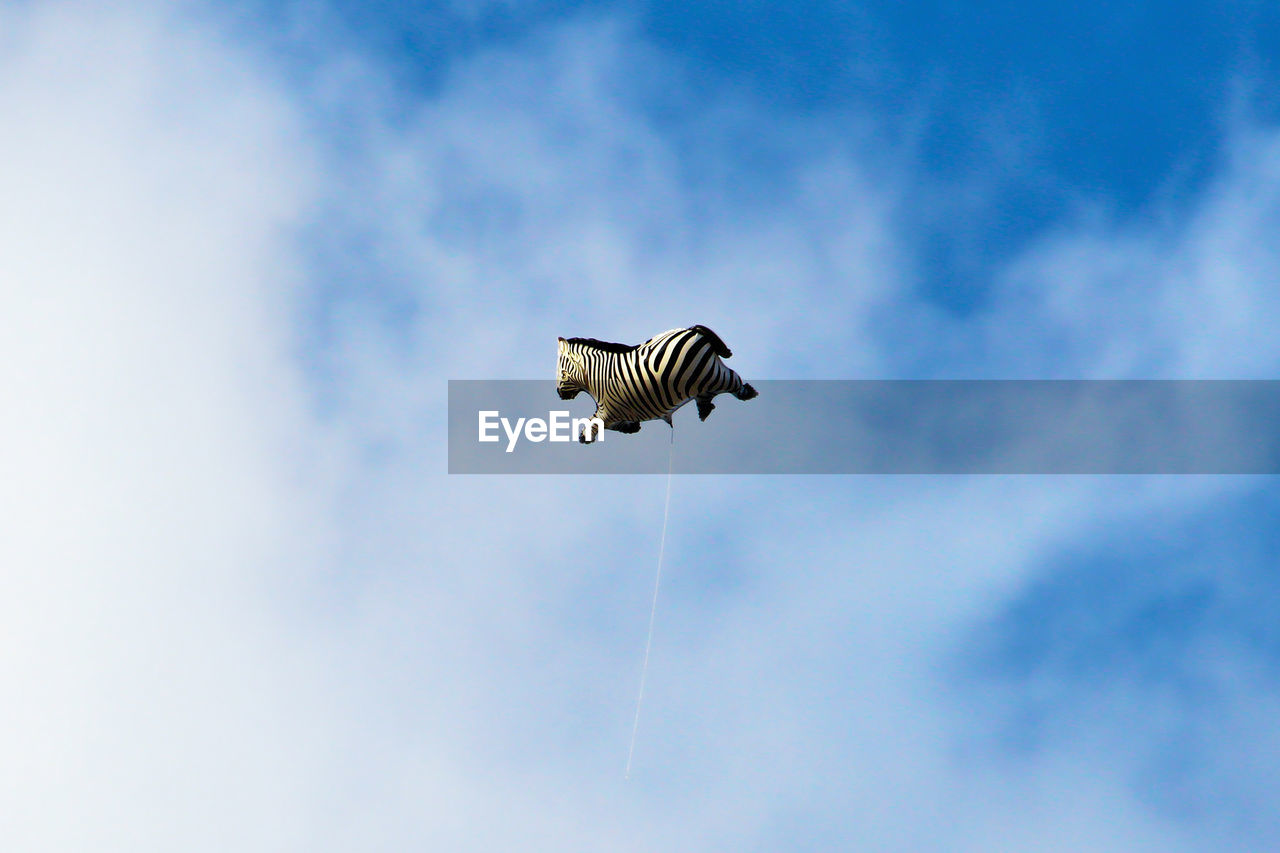 Low angle view of zebra balloon flying against cloudy sky