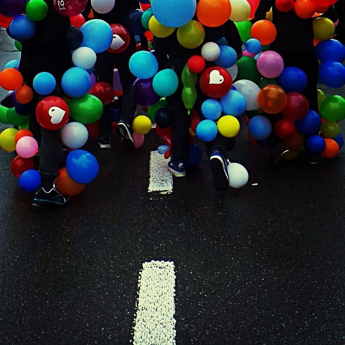 Rear view of people with colorful balloons on road