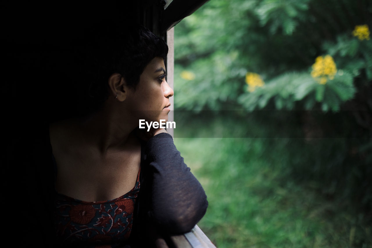 Thoughtful woman looking through window while traveling in train