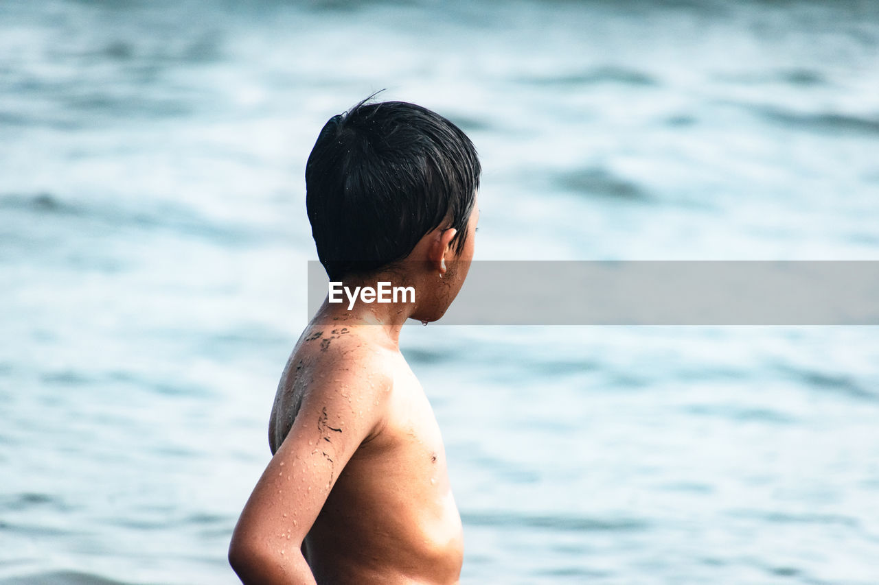 Shirtless boy standing at beach