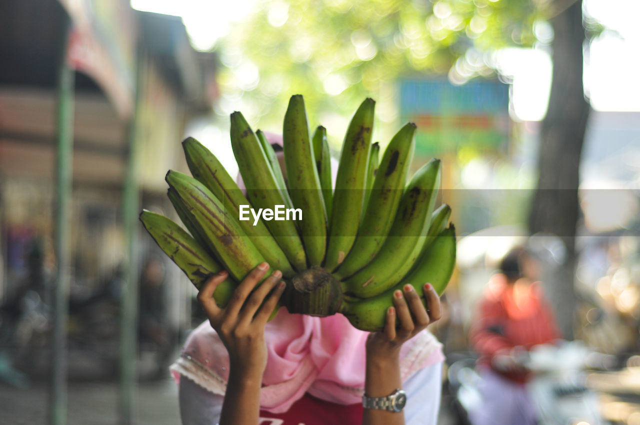 Woman with face covered by bananas