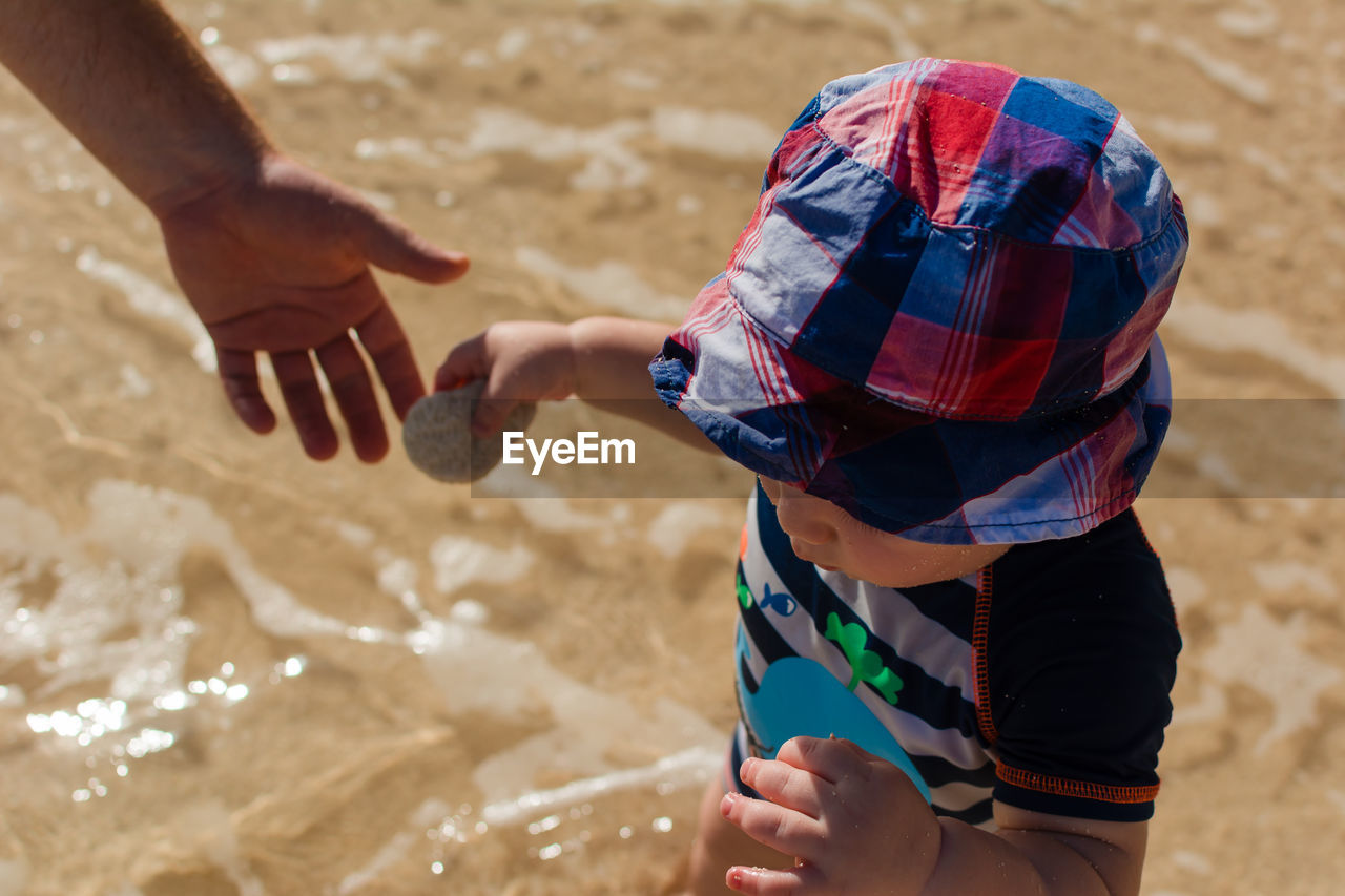 Cropped hand of mother with son at beach