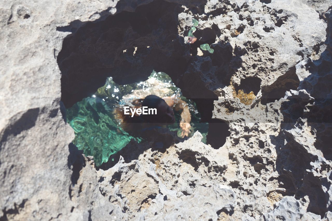 High angle view of woman swimming in sea amidst 
 rocks on beach