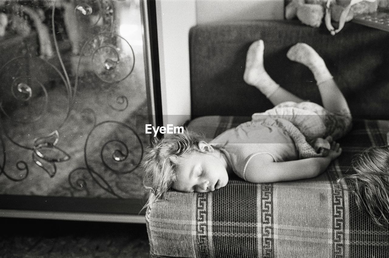 Full length of girl sleeping on sofa at home