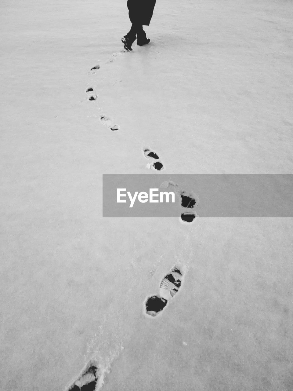 Low section of person walking on snow covered field