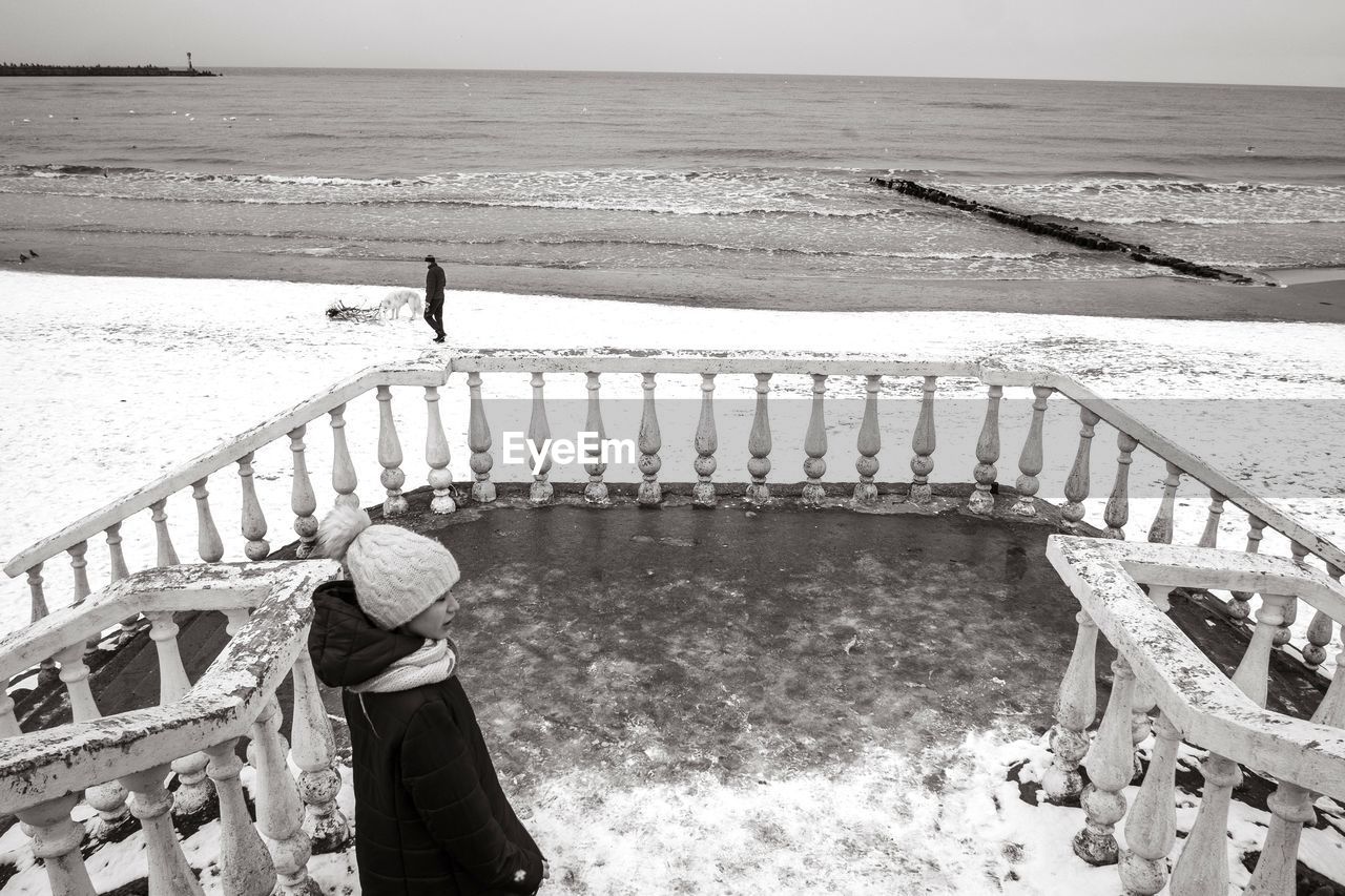 High angle view of girl standing by railing against sea