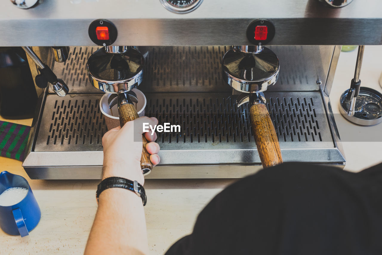 Cropped image of man using espresso maker at cafe