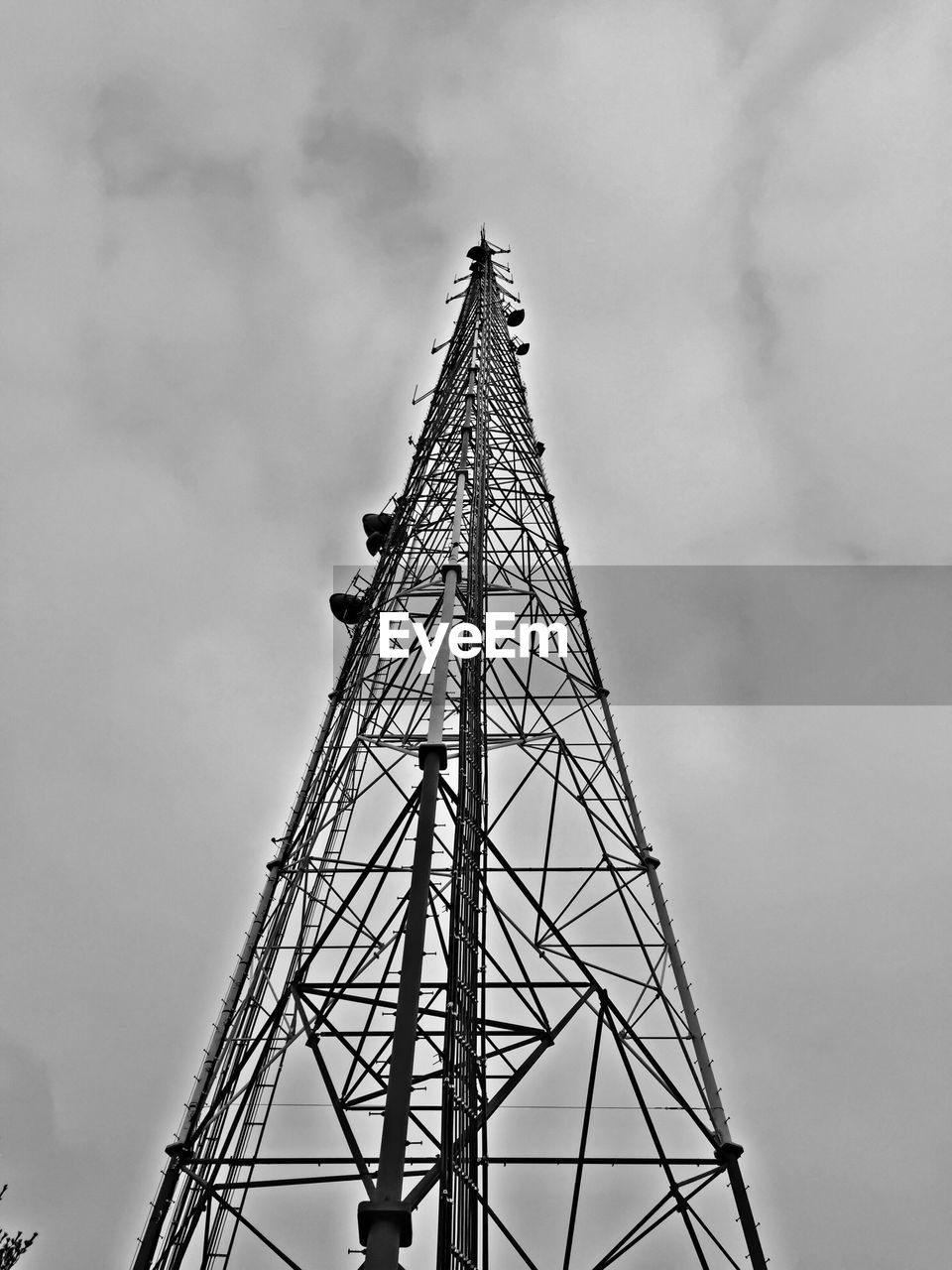 Low angle view of communication tower against cloudy sky