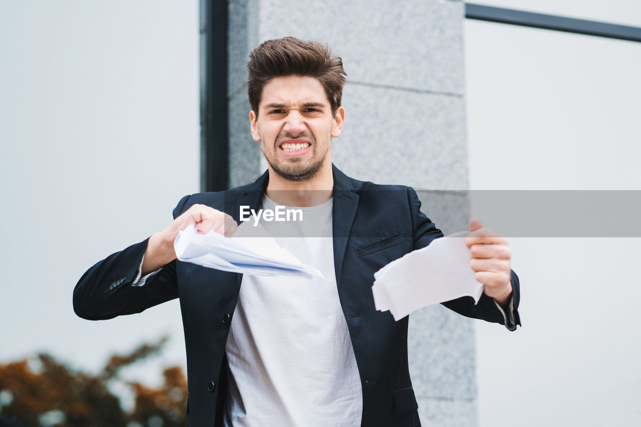 Portrait of frustrated businessman tearing papers