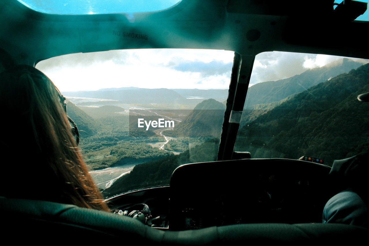 Woman looking at landscape through helicopter windshield
