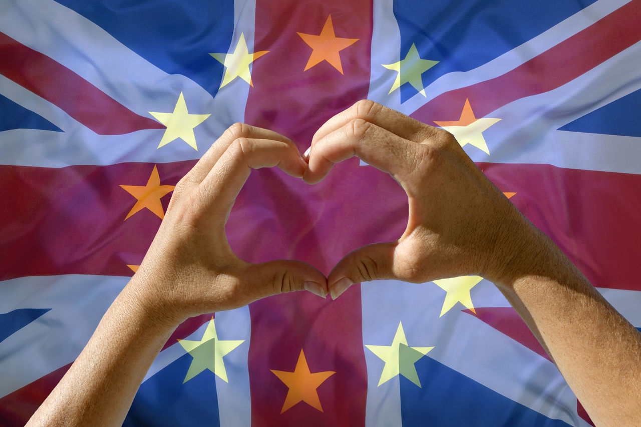 Close-up of hands making heart shape against british flag