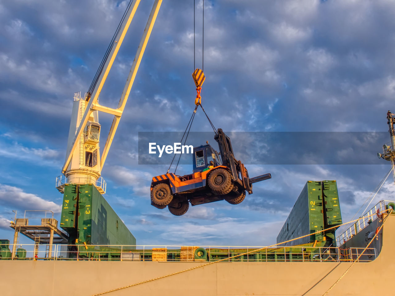 The ship's crane is moving forklift and special tool to operate cargo on board.