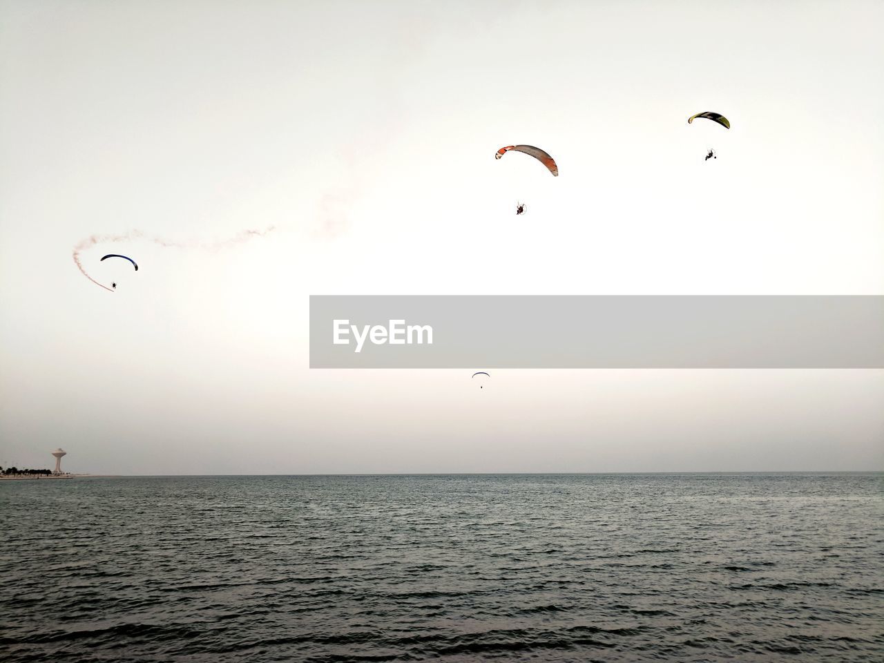 Paragliding over sea against clear sky