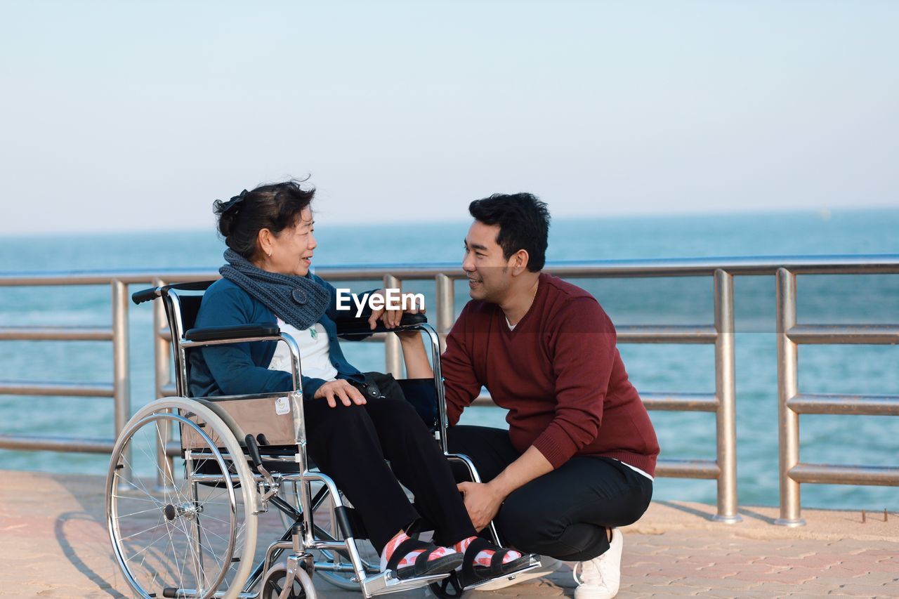 Senior woman with grandson sitting on wheelchair by sea