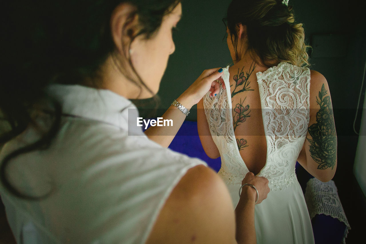 Rear view of woman zipping bride dress