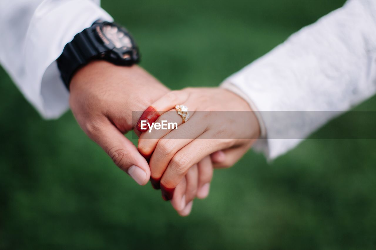 Cropped image of bride and groom holding hands