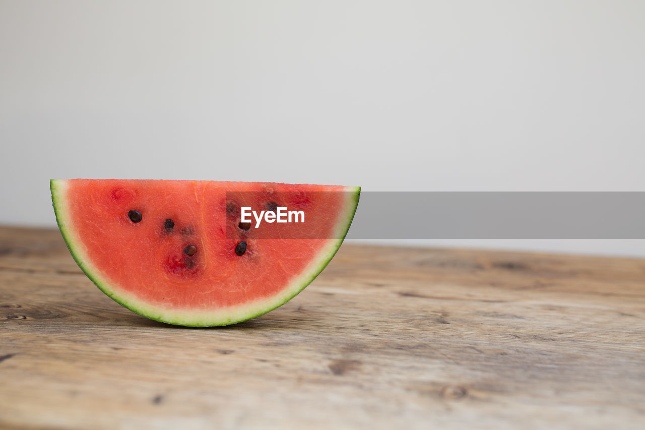 Close-up of watermelon on wooden table against white background