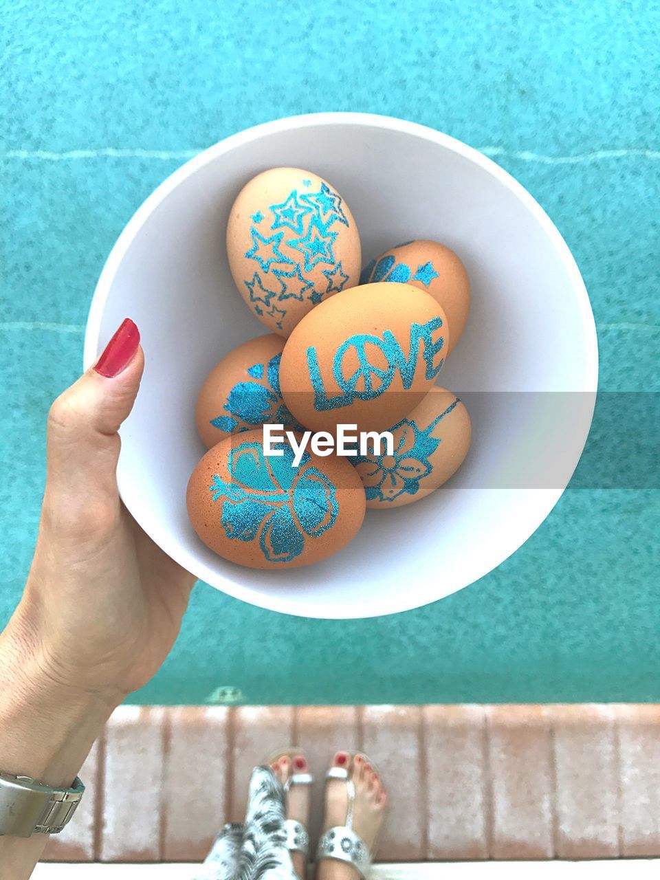 Close-up of hand holding painted easter eggs in bowl