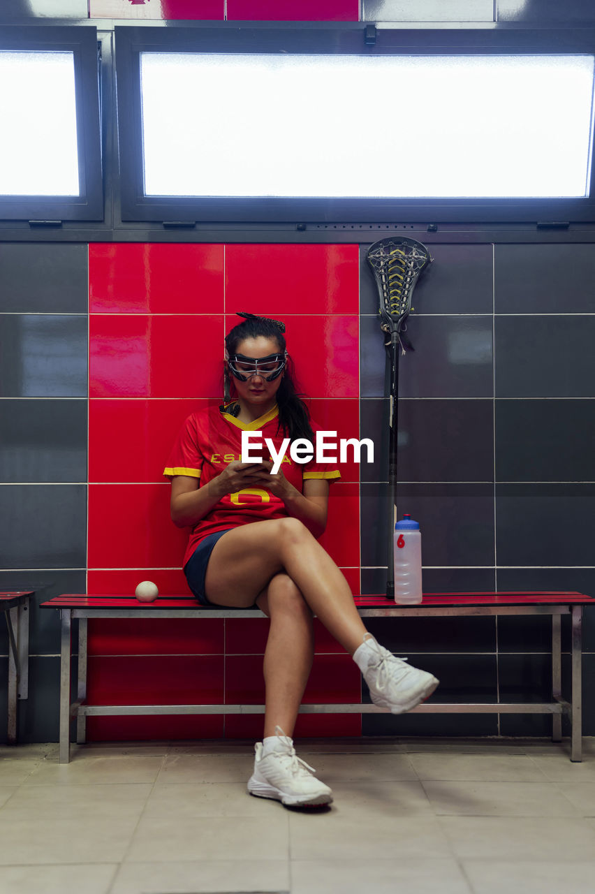 Young woman using mobile phone in locker room