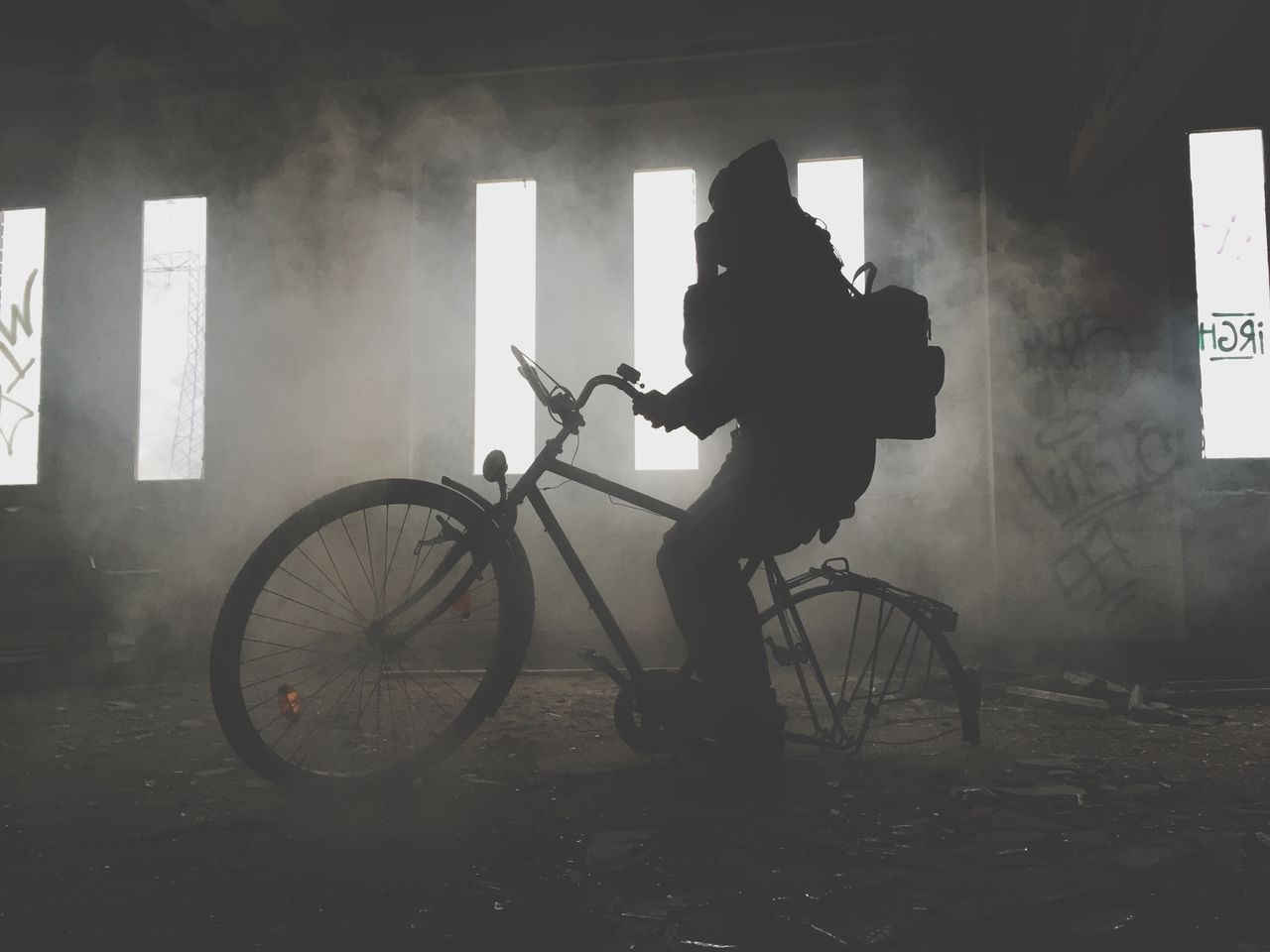 Silhouette person on bicycle in abandoned house