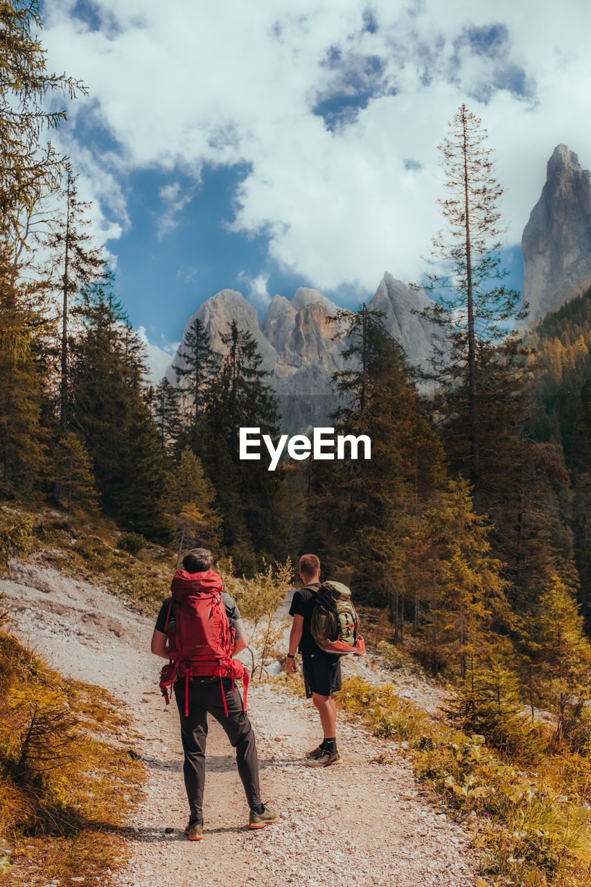 Rear view of people walking hiking on mountain against sky