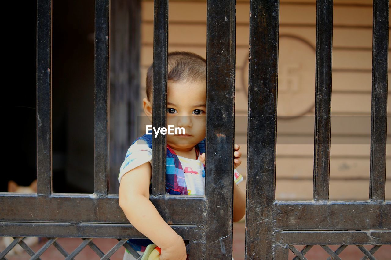 Portrait of young girl looking through fence