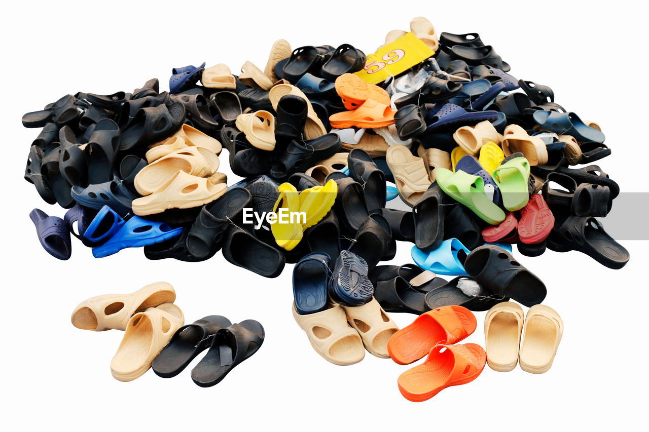 High angle view of multi colored flip flops against white background