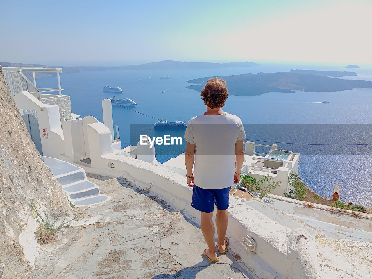 Rear view of man standing at coast against scenic view of sky and sea