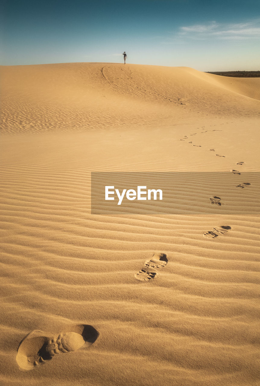 Scenic view of sandy desert with footprints of person walking