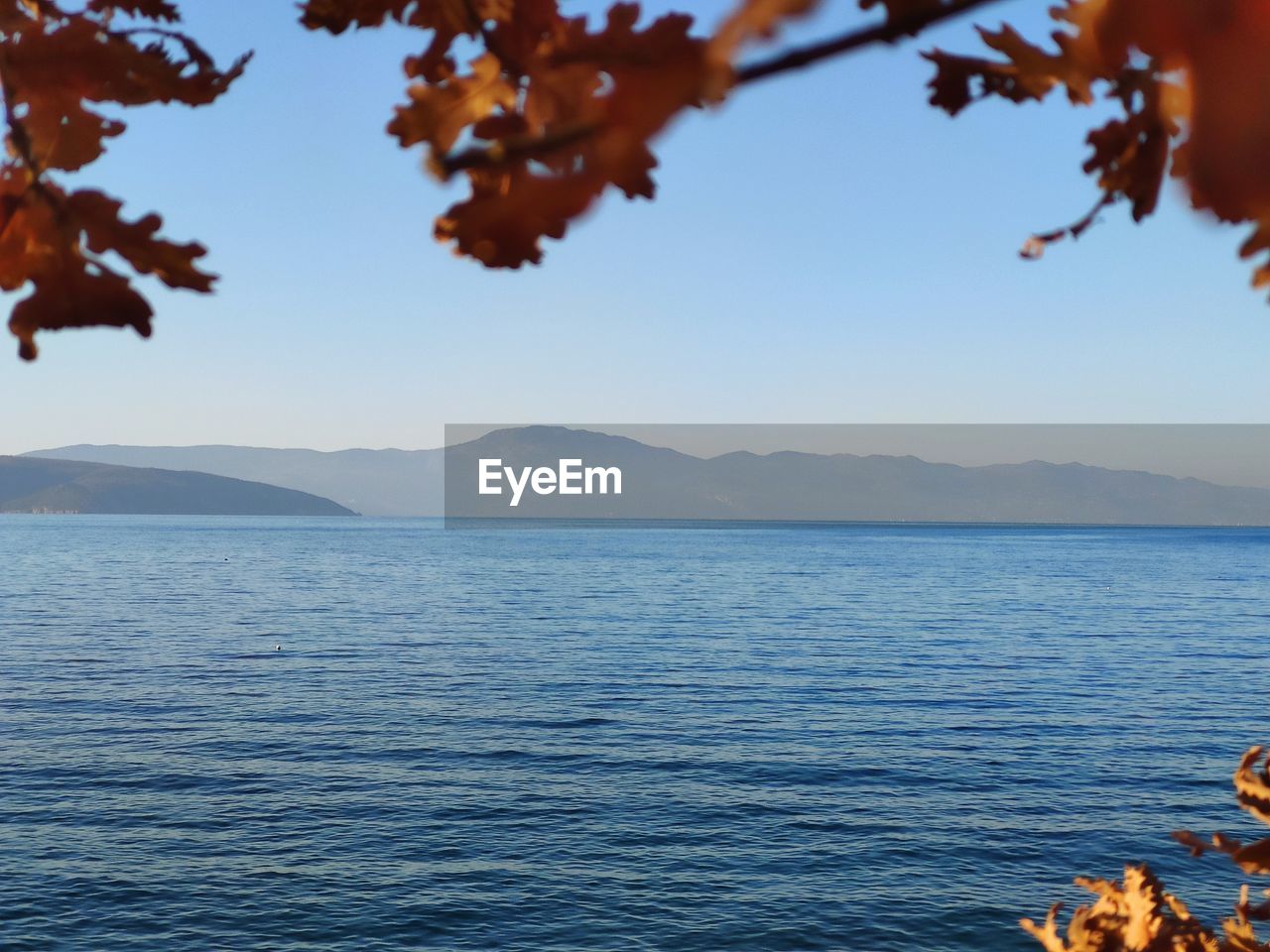SCENIC VIEW OF SEA BY MOUNTAINS AGAINST CLEAR SKY