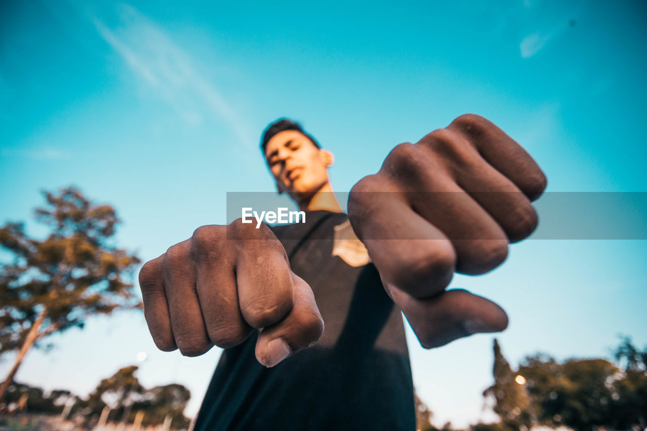 Low angle view of young man against blue sky