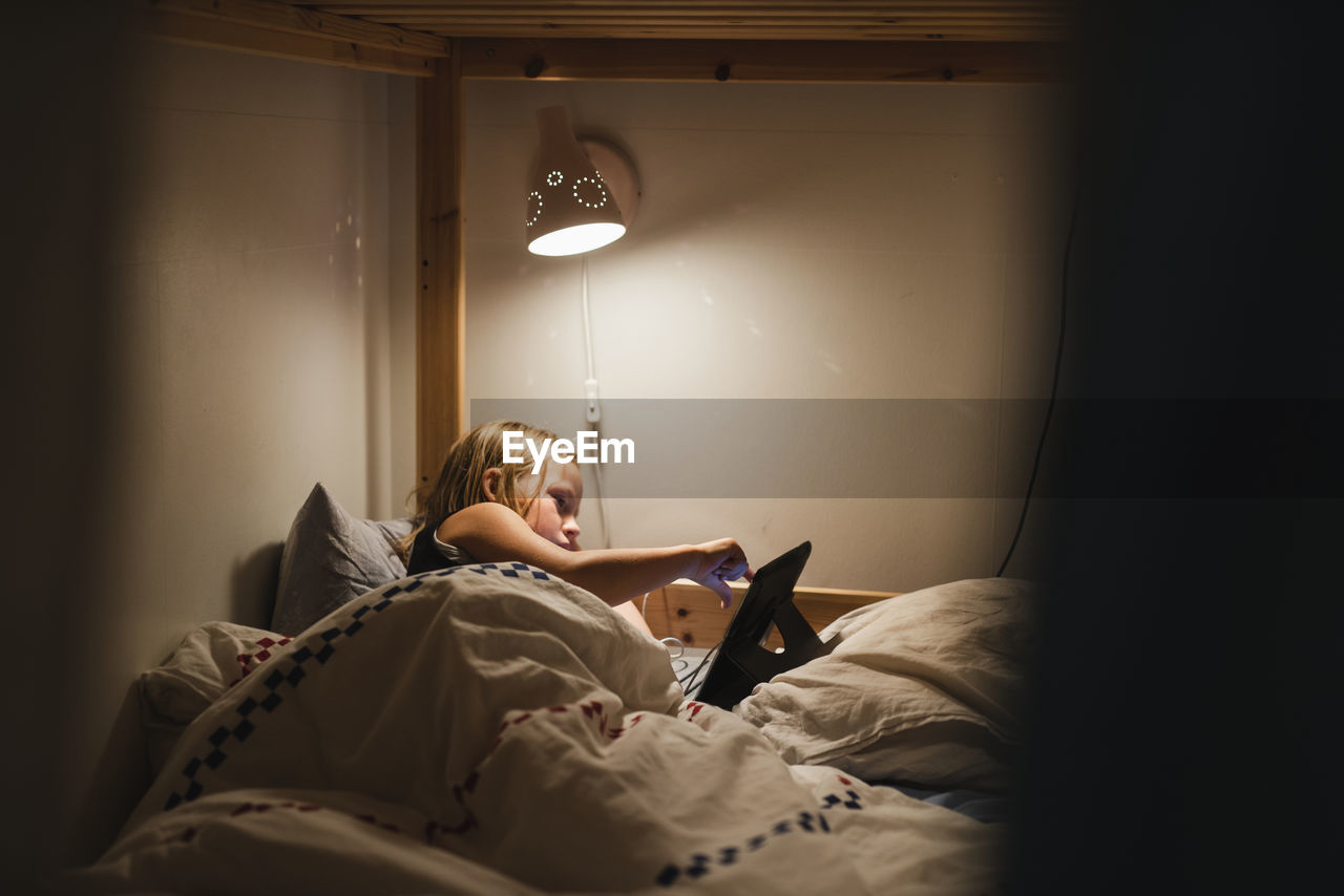 Girl using digital tablet on bed