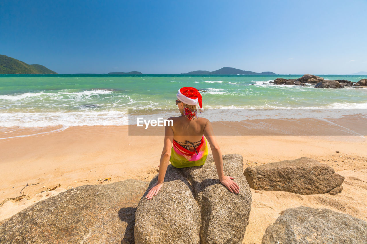Woman relaxing at beach against sky