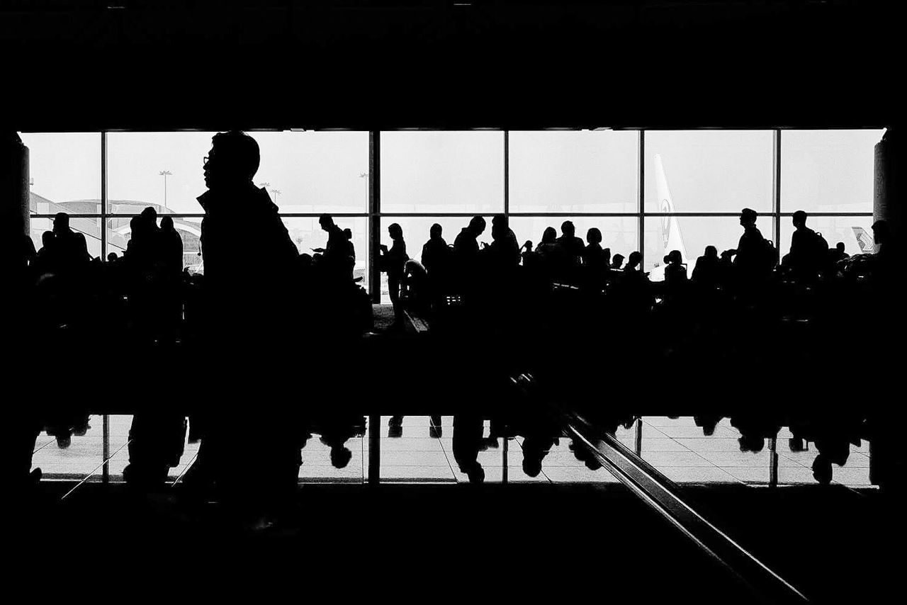 SILHOUETTE PEOPLE STANDING ON AIRPORT RUNWAY AGAINST SKY
