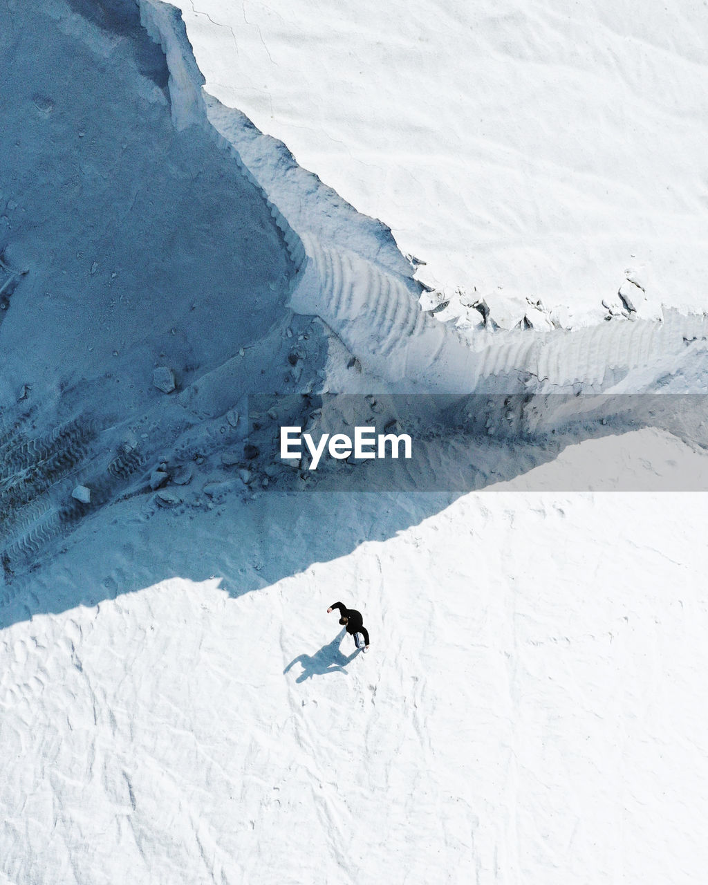 HIGH ANGLE VIEW OF PERSON SKIING ON SNOWCAPPED MOUNTAINS