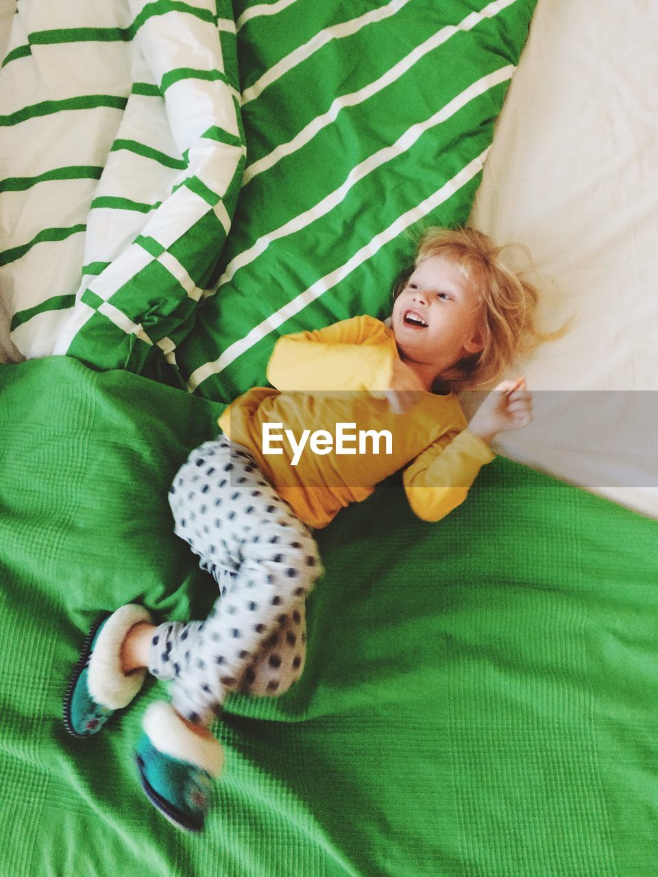 High angle view of smiling girl lying on bed