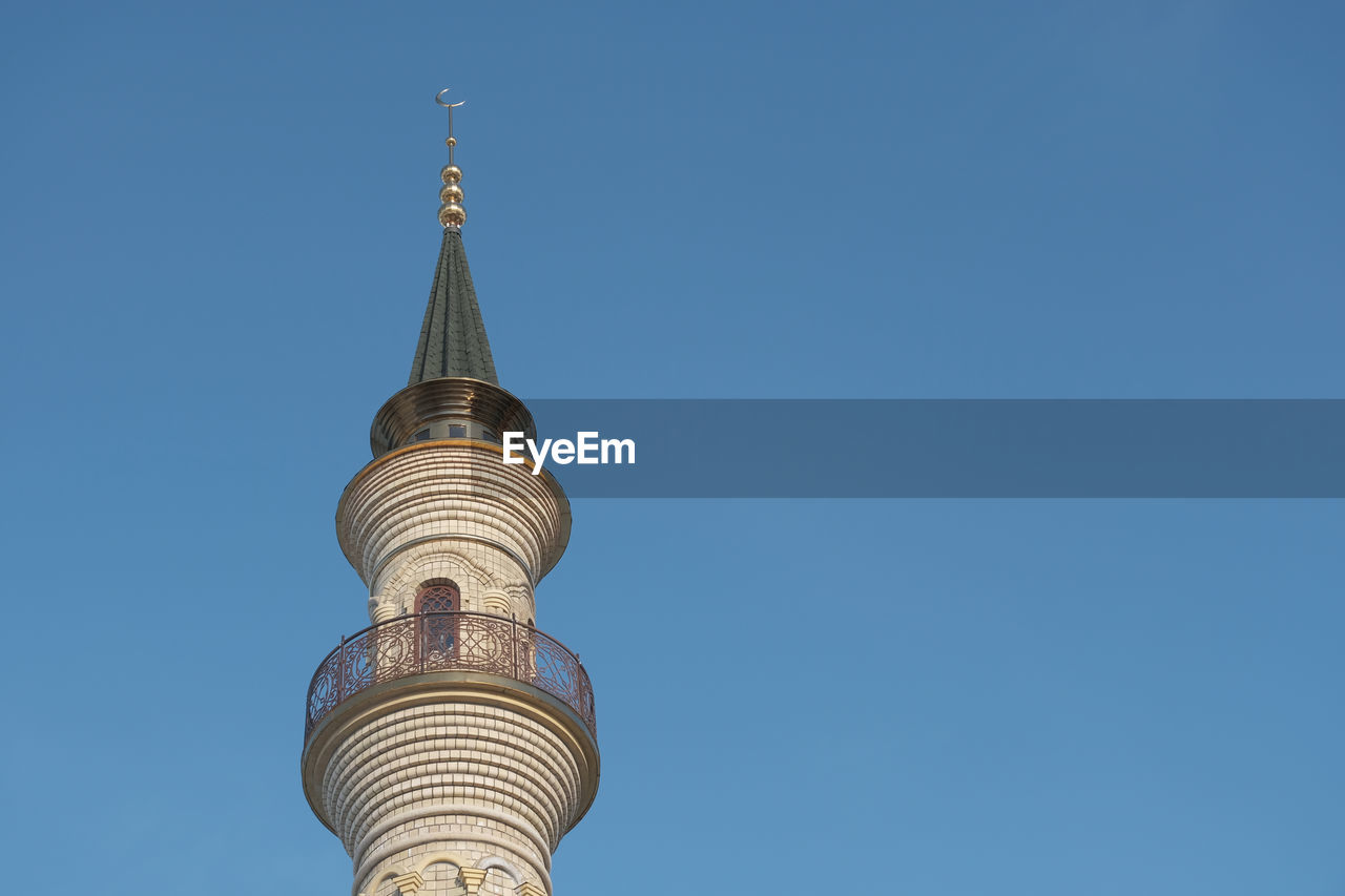 Minaret of the mosque against the blue sky. islam in europe