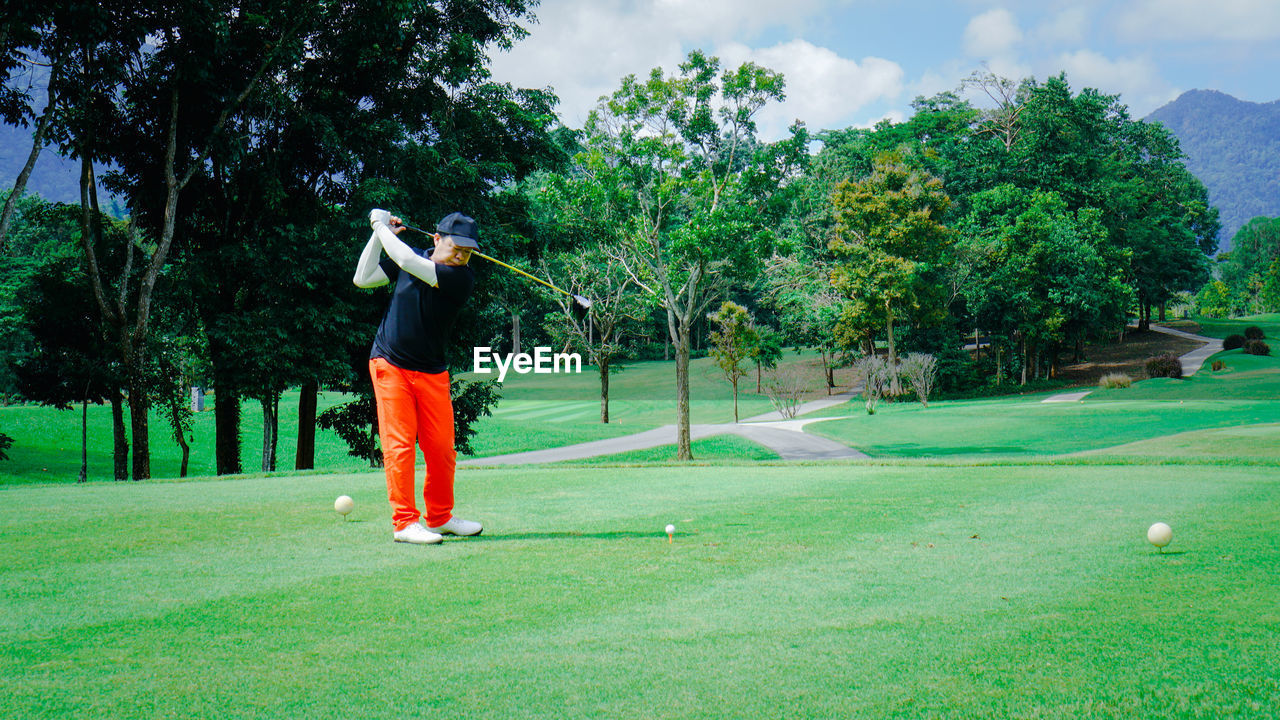 Male senior golfer swinging golf ball in a nature green grass fairway. professional golf player.