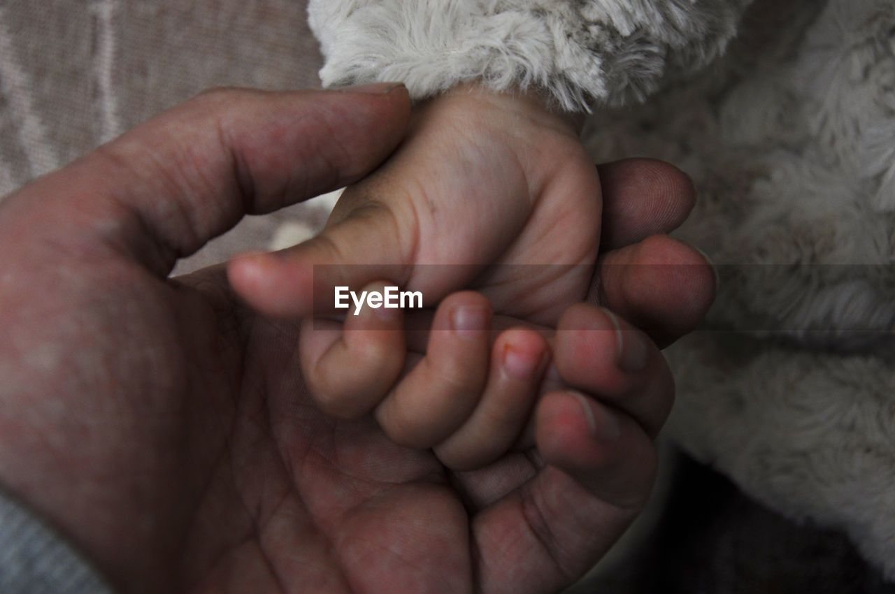 CLOSE-UP OF HANDS HOLDING BABY