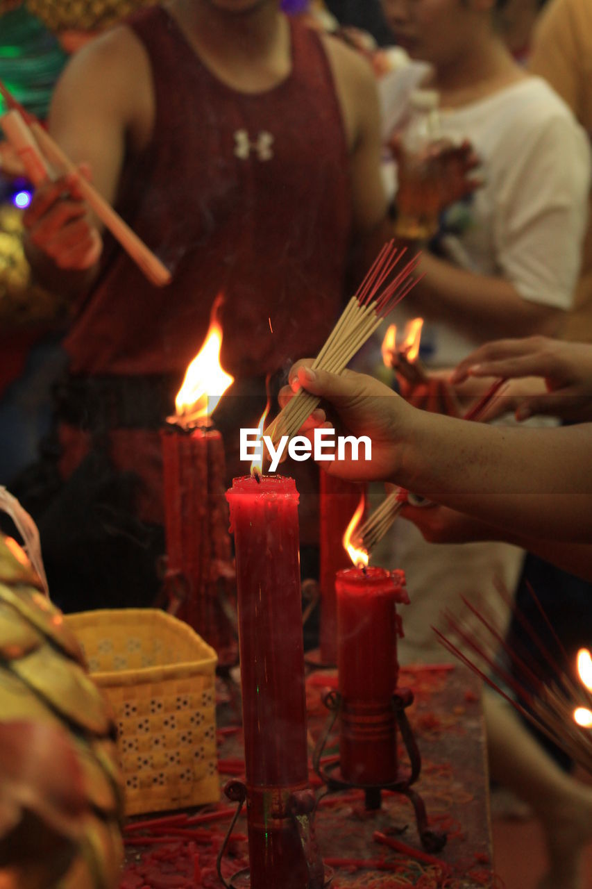 Cropped image of people burning incense