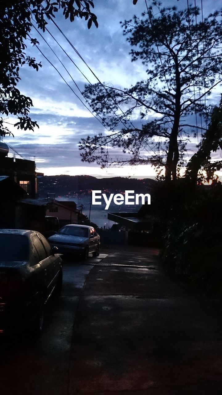 Cars on road against cloudy sky
