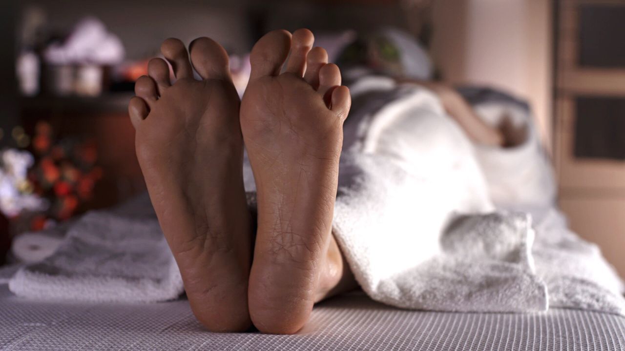 Woman lying on bed with focus on her feet at spa