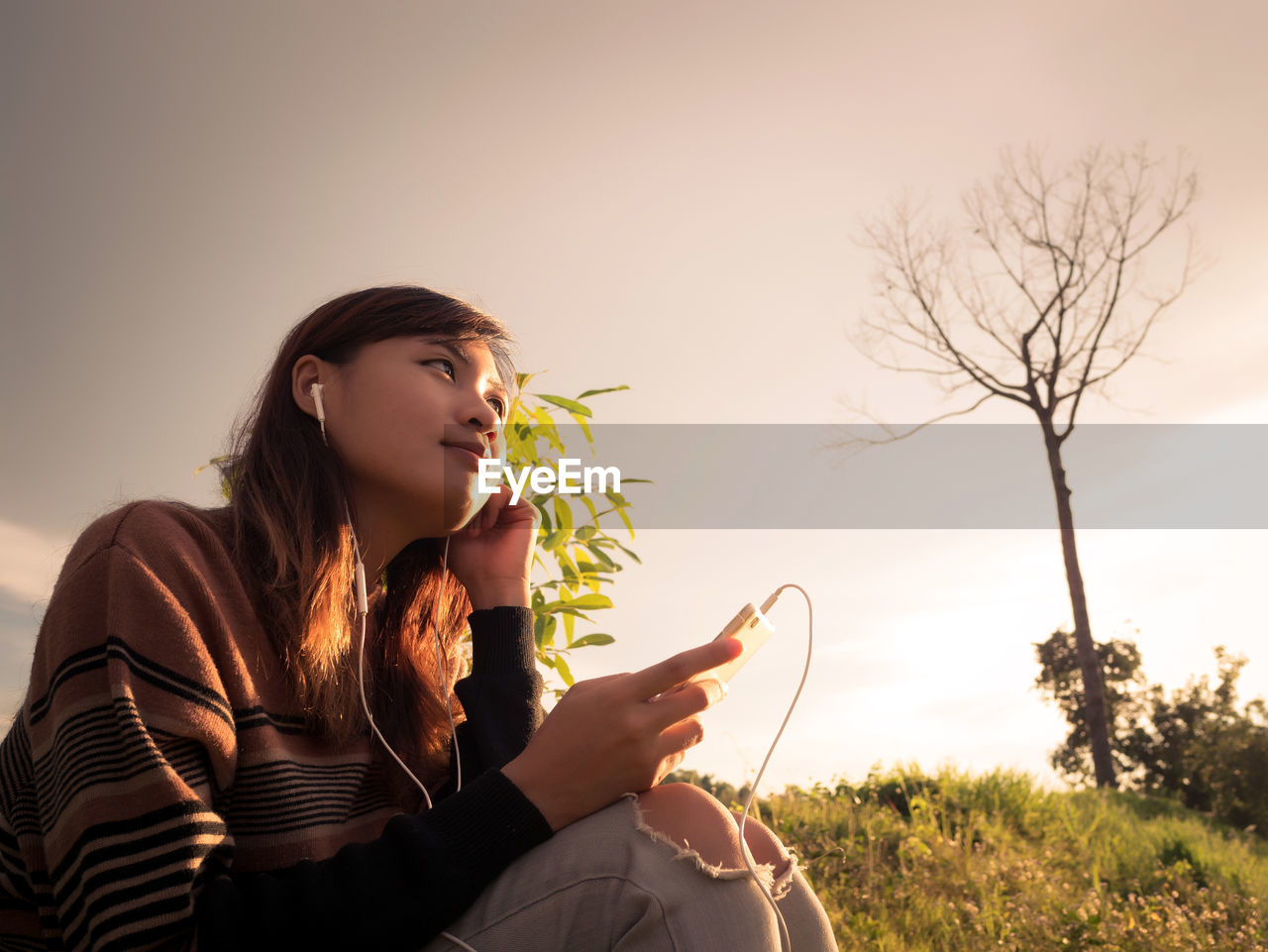 Young woman reading the book at riverside in the evening.