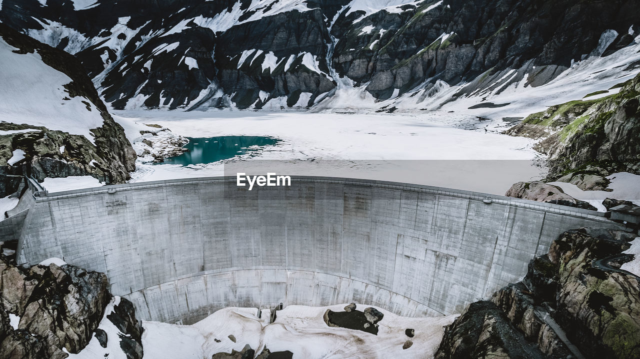 Scenic view of snow covered mountains with a dam