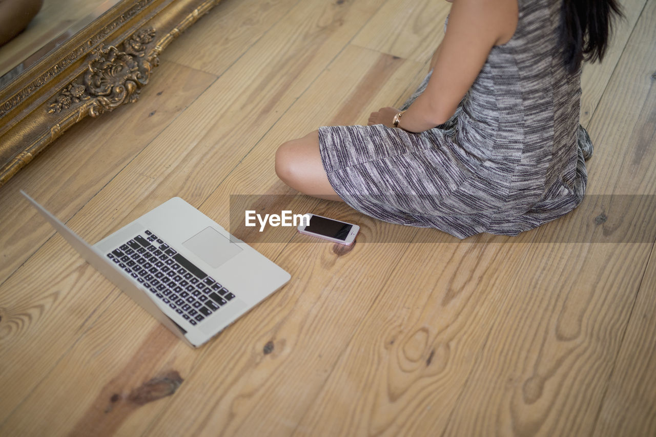 Young woman sitting on a wooden floor with her laptop