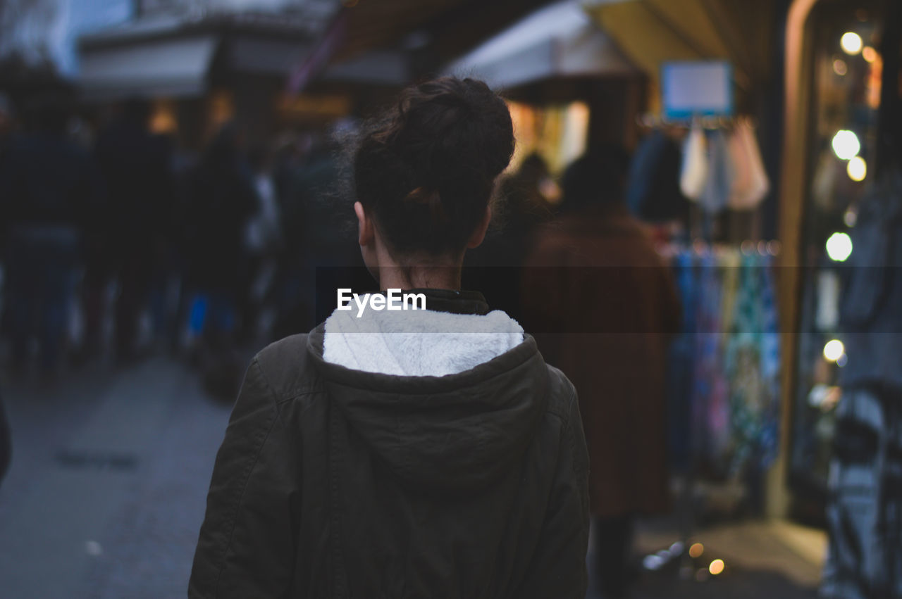 Rear view of woman standing on street at dusk