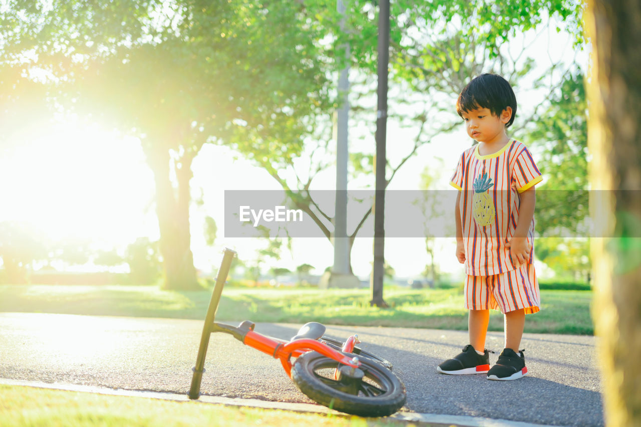 Full length of boy looking at bicycle