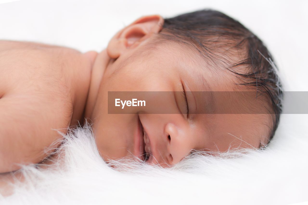 Close-up of cute baby boy lying on bed at home
